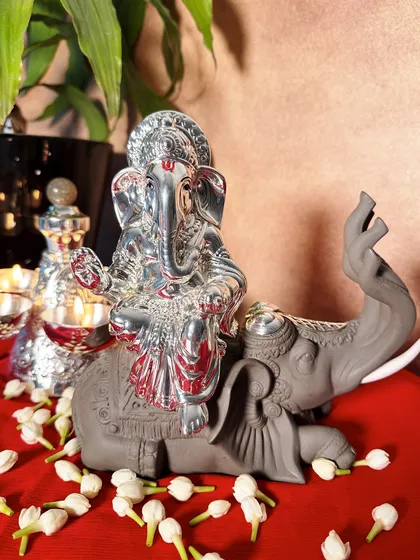 This beautifully composed scene shows a silver Ganesha idol on a grey elephant, surrounded by fragrant jasmine flowers and glowing diyas. It captures the full essence of a devotional offering.