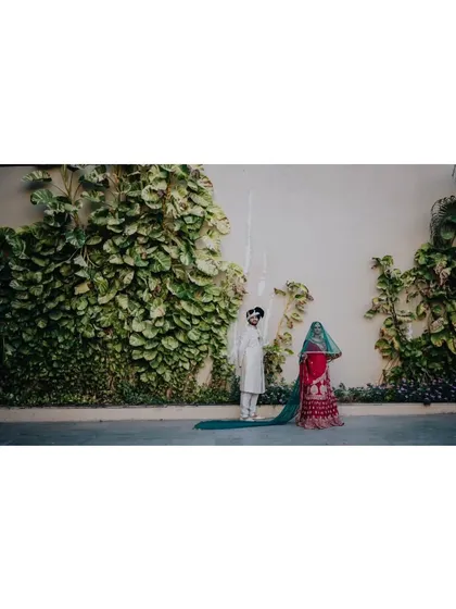 A stylish, minimalist portrait of the couple against a wall of green ivy.