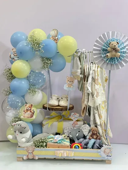 This elaborate hamper for a baby boy includes a miniature clothing rack with tiny outfits, soft toys, and a beautiful balloon display. It’s a complete and impressive gift to celebrate a new life.
