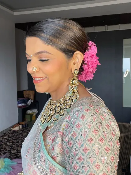 A wedding day updo with a garland of vibrant pink flowers. This is a beautiful way to add a pop of color and freshness to a bridal look.