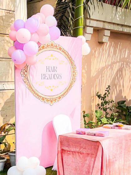 A "Hair Beading" activity station at the princess party. The pink backdrop with a gold ornate frame and matching table cover makes even the activities feel luxurious and on-theme.