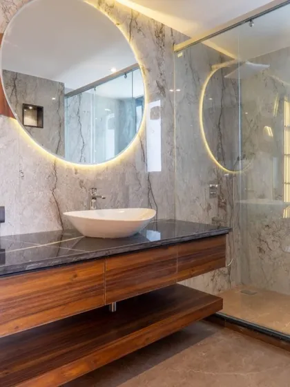 A bathroom should feel like a personal spa. Here, I used large-format marble tiles, a floating wood vanity, and a backlit circular mirror to create a space that is clean, modern, and radiates calm.