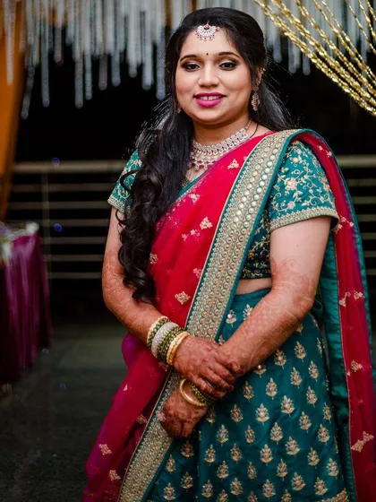 A classic portrait of the bride at her reception. Her makeup is elegant and timeless, with a focus on clean lines and a radiant finish that complements her intricate lehenga.