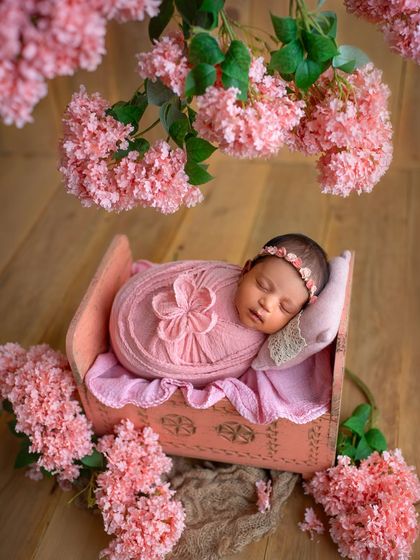 This little one is sleeping soundly in a vintage-style pink cot, surrounded by beautiful pink blossoms. A truly classic and feminine setup for a baby girl.