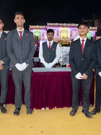 My professional service staff standing ready at their station during a large wedding event in Panvel. They are in full uniform, including gloves, to ensure hygiene and professional service.