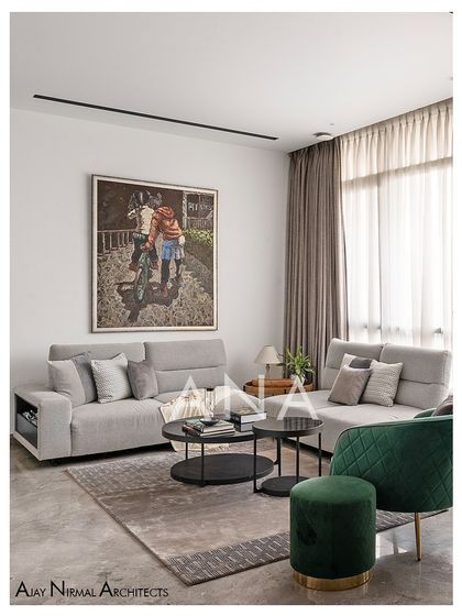 The minimal sitting area in Apartment 704, where a comfortable grey sofa is paired with a vibrant green lounge chair. A large piece of art adds a personal touch to the clean, modern space.