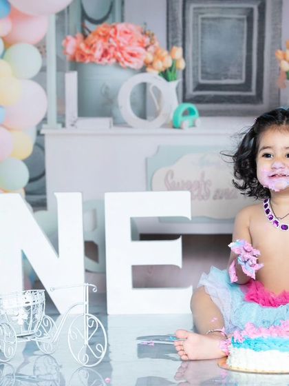 Another angle of the colorful first birthday cake smash, capturing the baby's happy expression.