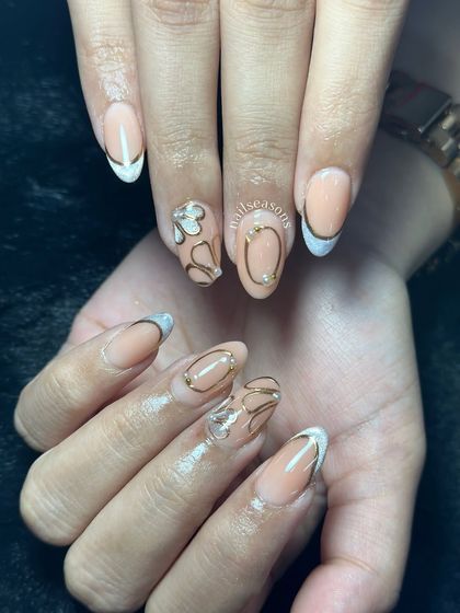 A modern and artistic take on a nude manicure, with abstract gold line work and a reverse French tip.