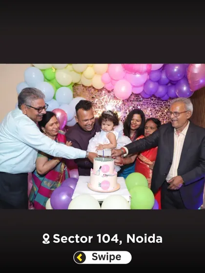 A large family group celebrating a first birthday. Everyone is gathered around for the big cake-cutting moment.