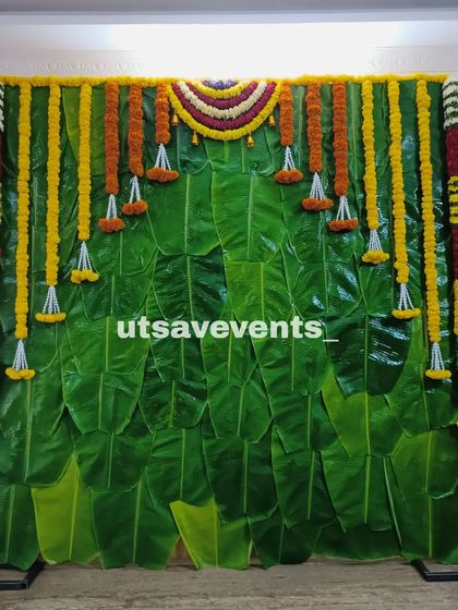 A simple yet elegant backdrop made of fresh banana leaves and marigold garlands, perfect for a traditional home function.