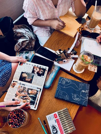 A snapshot of a creative meetup with friends, featuring journaling, art supplies, and coffee. This shows my connection to the artistic community.