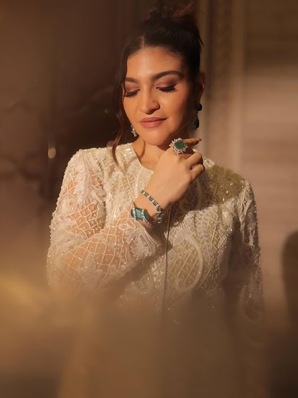 A close-up showing the details of her makeup and jewelry. The look features bold, shimmery eyes and glossy nude lips for the ultimate glam mode.