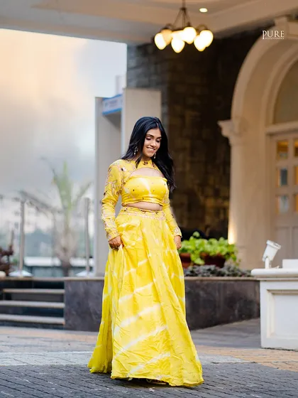 A full-length shot of the bride twirling in her beautiful yellow lehenga. This photo captures her joy and the flow of her stunning outfit.