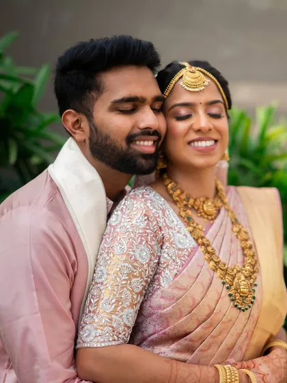 A tender moment between the couple. The bride's makeup in soft pink tones perfectly matches her beautiful silk saree, creating a harmonious and romantic look.