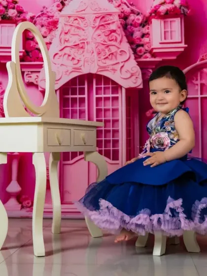 A royal blue dress provides a beautiful contrast against the pink Barbie dream house backdrop.
