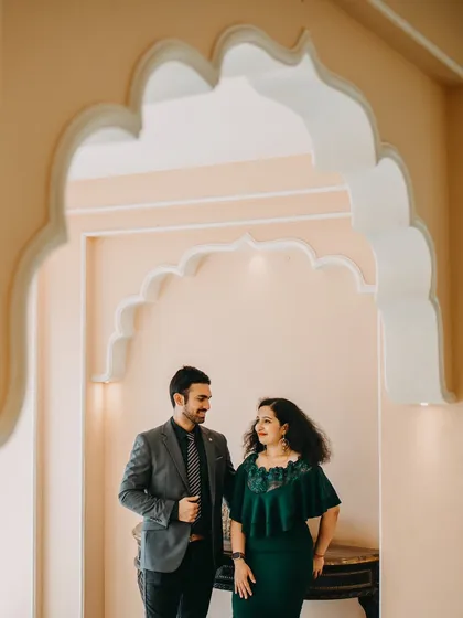 The couple shares a look as they stand within a series of beautiful scalloped archways. This shot uses architectural framing to create a visually interesting and romantic portrait.