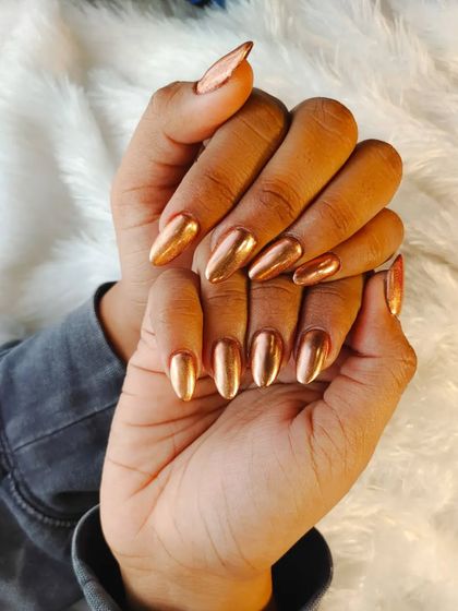 A stunning rose gold chrome finish on almond-shaped nails for a trendy and high-shine look.