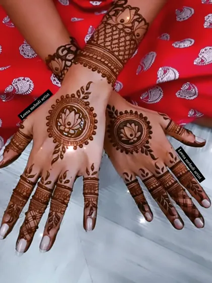 A beautiful mandala design featuring a lotus in the center. The pattern is delicate and feminine, with leafy vines extending towards the fingers.