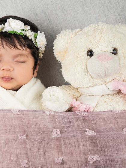 Tucked in and cozy with a teddy bear friend. This simple and sweet newborn photo highlights the baby's peaceful expression and delicate features.