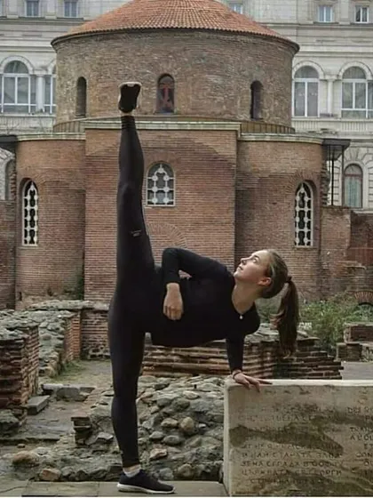 A student practices a standing split against a historic backdrop, symbolizing that martial arts is a lifelong journey of learning with deep roots.