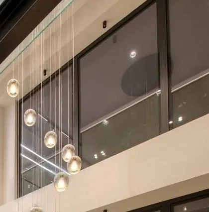 The cascading glass orb chandelier, a signature feature in our multi-level designs, creating a sense of vertical connection and elegance.