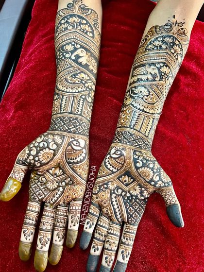 A close-up of Pooja's full bridal mehendi, showcasing the intricate details of the peacocks on the palms and the elephants on the arms.