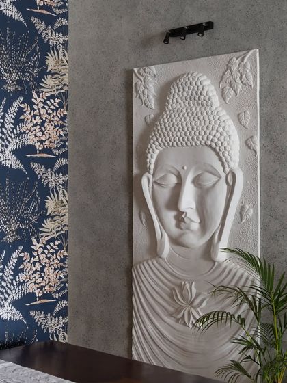 The wall in this foyer serves as a captivating canvas. A striking white Buddha wall art is set against a textured grey wall and a deep blue floral wallpaper, creating a versatile and personal focal point.