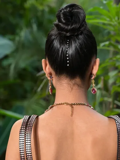 A minimalist and chic detail shot of a high top-knot. A simple line of stick-on crystals along the nape of the neck adds a surprising and modern touch for cocktail or evening looks.