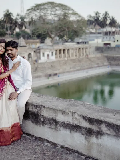 An intimate pose against the expansive backdrop of a historic temple tank, creating a photo that feels both grand and personal.
