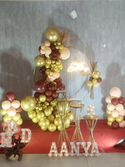 A sophisticated birthday setup with a gold and maroon balloon ring, perfect for a milestone celebration.