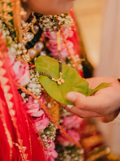 A symbolic detail shot of the sacred mangalsutra resting on a betel leaf. We believe in capturing the small, meaningful details that hold immense cultural and emotional value, adding depth to your wedding album.
