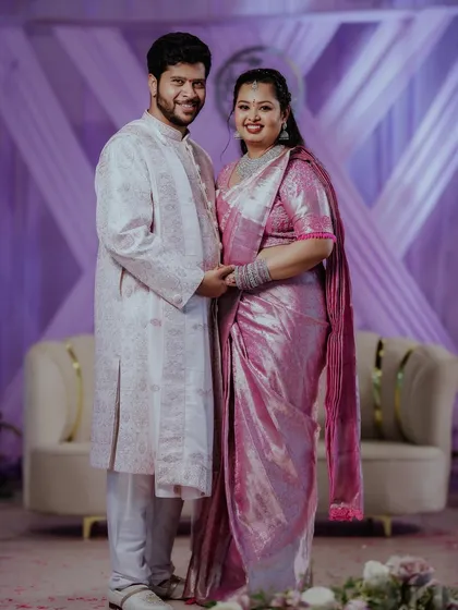 A happy couple posing in front of their beautiful lavender-themed engagement backdrop, capturing a genuine moment and showcasing the final result of our decor work.