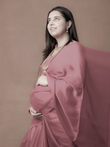 A hopeful and serene portrait of a mom-to-be in a dusty pink saree. The soft, flowing fabric and her upward gaze give this image a dreamy and artistic quality.