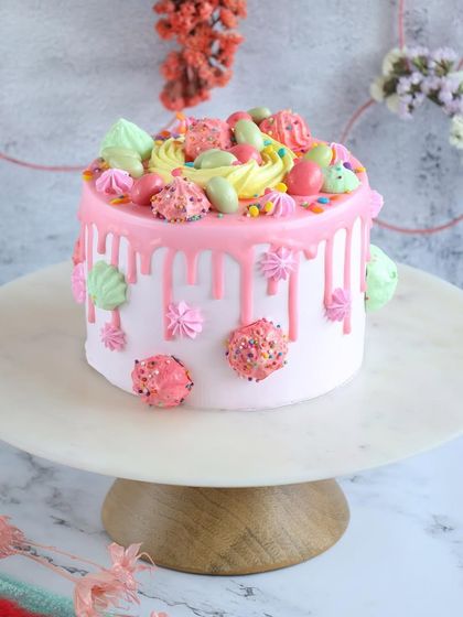 A pretty pink drip cake for Easter, adorned with colorful meringues and sprinkles. A sweet and cheerful treat for the whole family.