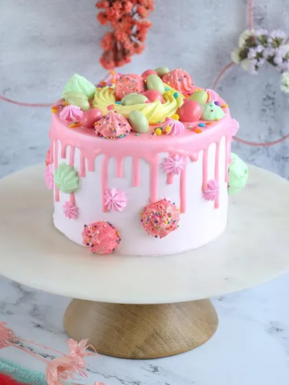 This pink Easter drip cake is overloaded with colorful meringues and sprinkles for a fun and festive look.