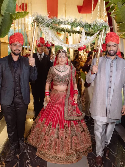The bride makes her grand entrance under a beautiful 'phoolon ki chadar' held by her brothers, a classic and heartwarming Sikh wedding tradition.