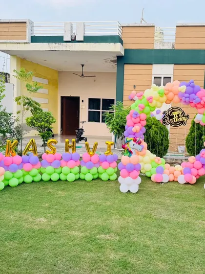 A closer look at the outdoor unicorn birthday setup. The decoration includes a large number '1' balloon and the name "Kashvi" in gold foil letters, making it extra special for her first birthday.