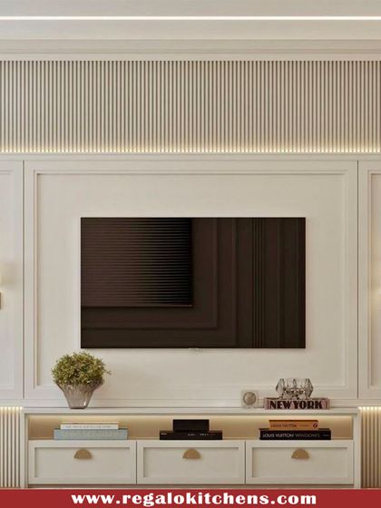 This classic, elegant TV unit features traditional molding and fluted panel details. The integrated wall sconces and soft backlighting create a cozy and sophisticated ambiance.
