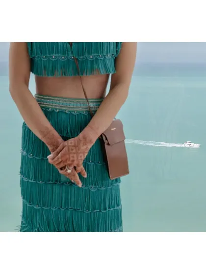 A detail shot of Alya's hands and outfit, with a speedboat creating a trail in the turquoise water behind her. It’s a stylish and creative portrait that tells a story of a destination wedding.