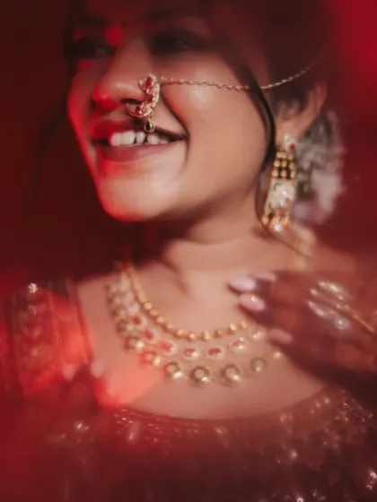 An artistic, blurry shot that focuses on the bride's joyful smile and her traditional nath. This captures the emotion of the day, with the makeup providing a beautiful, radiant base.