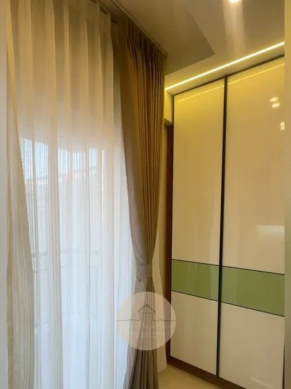 A simple shot of a completed bedroom, showing the elegant sheer curtains paired with a modern two-tone sliding wardrobe.