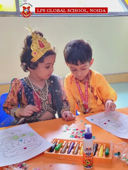 Two young students, dressed as Radha and Krishna, collaborate on their craftwork, embodying the spirit of the festival.
