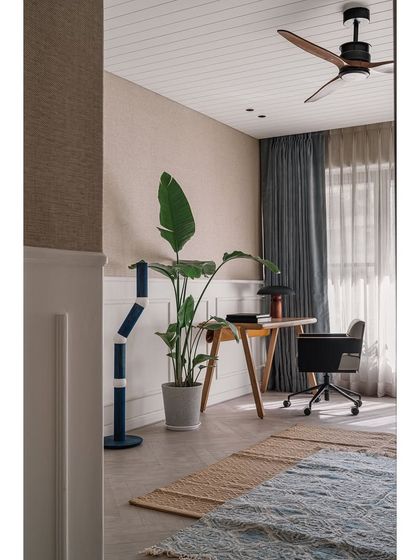 The den provides a quiet corner for work or relaxation, with natural textures and a large plant bringing the outdoors in.