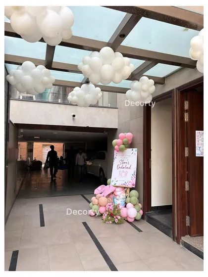 An entrance to a high-tea party with white balloon clouds hanging from the ceiling, creating a dreamy atmosphere.