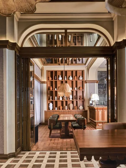 A view through an arched doorway into a private dining area, where a wall of curated pottery adds a touch of artisanal charm.