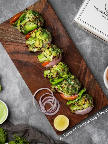 Another view of our Tandoori Malai Broccoli, served on a wooden board with fresh onion rings and a lemon wedge for an extra zing.