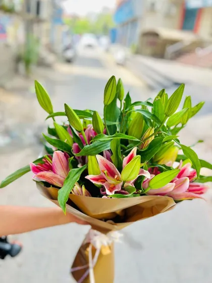 This bouquet showcases the simple beauty of fresh lilies. The pink lily buds are just about to bloom, arranged with their natural green leaves and wrapped in simple brown kraft paper for a fresh, rustic, and elegant look.