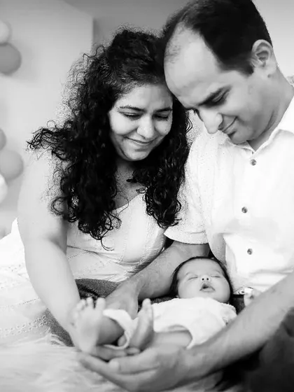 A beautiful black and white photo of new parents admiring their sleeping baby.