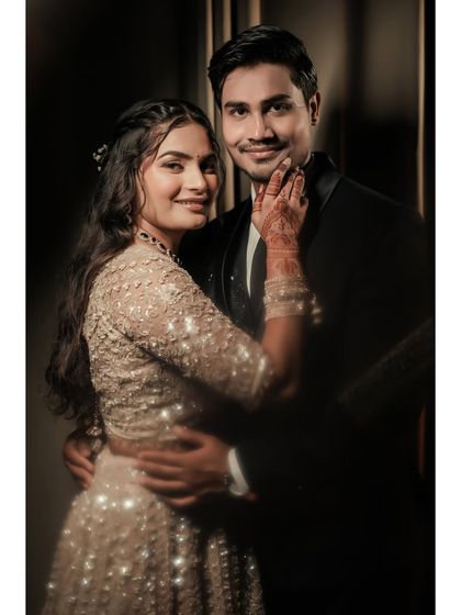 A classic, elegant portrait of Pallavi and Amit. Her hand gently on his chin, they share a look of love and admiration in a beautifully lit, formal setting.