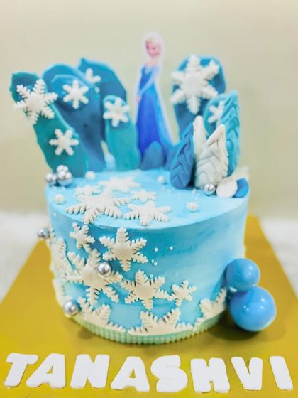 A close-up of the beautiful snowflake details on this Elsa-themed cake, showing the intricate piping work and shimmering silver accents.